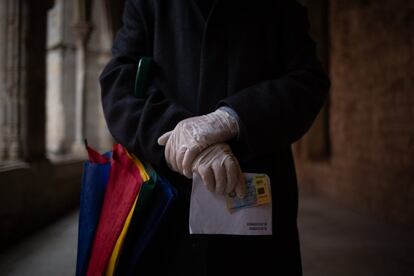 Una persona se dirige a votar a una mesa electoral con guantes, el DNI y el sobre con el voto.