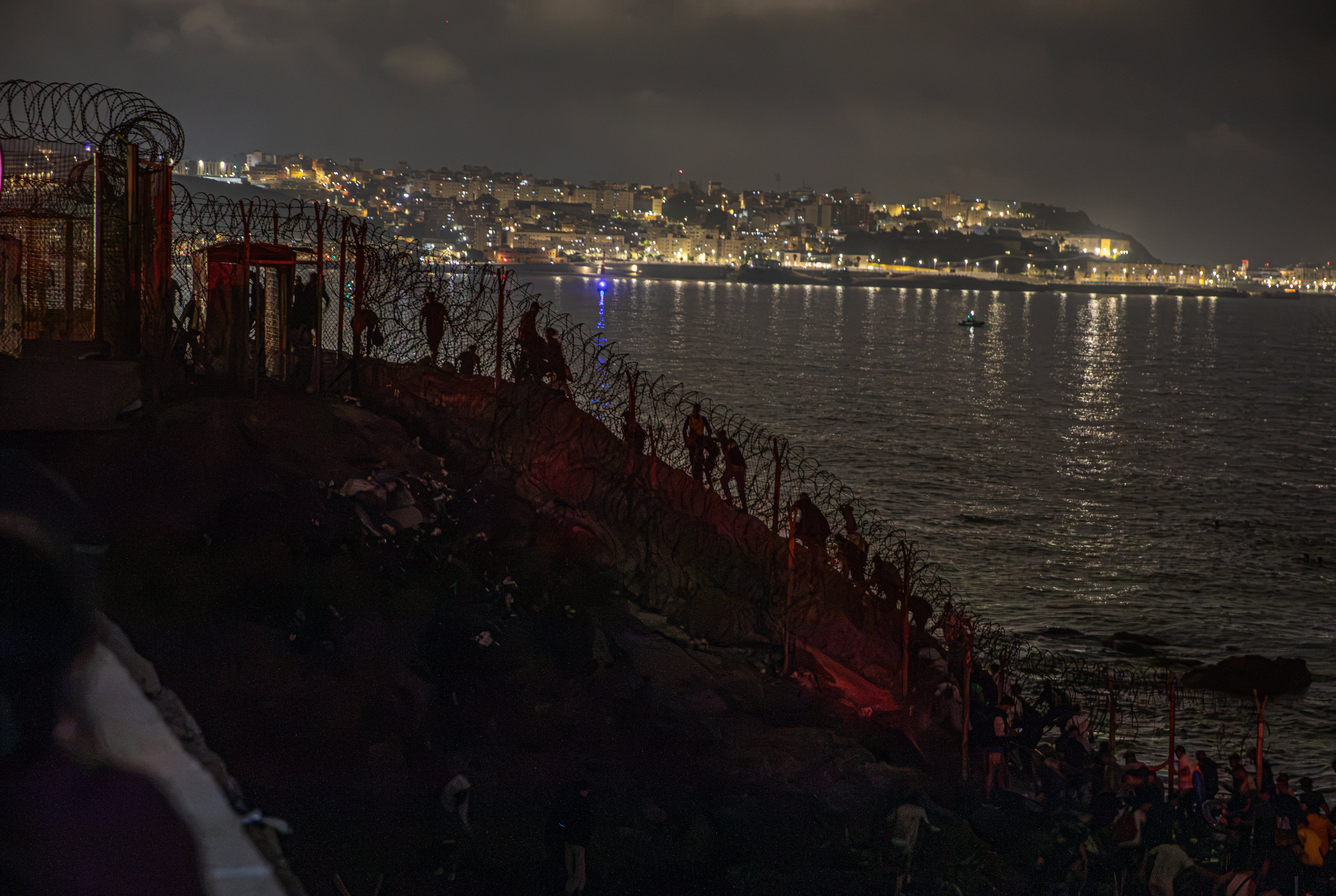 Grupos de migrantes irregulares atraviesan desde Castillejos la frontera en dirección a Ceuta en la madrugada del viernes.