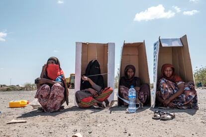 Varias mujeres eritreas refugiadas, desplazadas recientemente debido al conflicto en la región de Afar, están sentadas bajo cajas de cartón, mientras esperan a ser registradas por las autoridades en el recinto del Hotel Agda, en la ciudad de Semera (Etiopía), el 14 de febrero de 2022. 