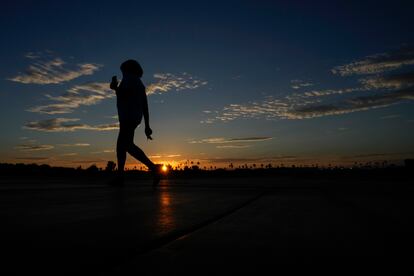 Janice Edwards listens to a podcast on her phone as she walks at sunrise Tuesday, July 11, 2023, in Yuma, Ariz.