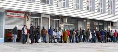 Varias personas forman una larga cola ante una oficina del paro.