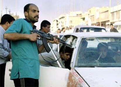 Un hombre apunta con su rifle al sospechoso de robar un coche en Bagdad, mientras otros registran el interior del automóvil.