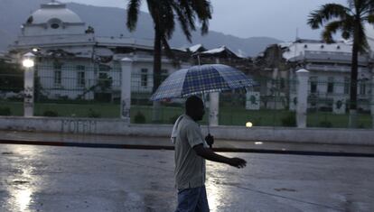 Un hombre camina, entre la lluvia, en los alrededores del ya derruido Palacio Nacional en Puerto Príncipe.