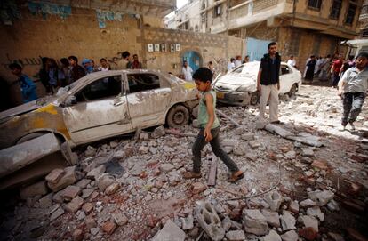Un niño pasa frente a la zona afectada por el ataque aéreo de la coalición liderada por Arasabia Saudita sobre Sanaa (Yemen).