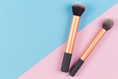 Make up brushes on pink and blue background. Top view.