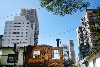 Un trabajador sobre una casa abandonada entre edificios residenciales en São Paulo (Brasil).