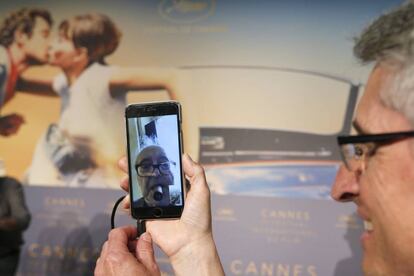 El productor Fabrice Aragno sujeta su móvil durante la rueda de prensa en Cannes de Jean-Luc Godard, que ha entrado vía FaceTime desde su casa.