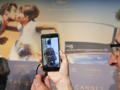 El productor Fabrice Aragno sujeta su móvil durante la rueda de prensa en Cannes de Jean-Luc Godard, que ha entrado vía FaceTime desde su casa.