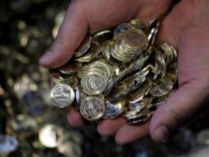 Un empleado de la Casa de la Moneda sostiene monedas de un euro. EFE/Archivo