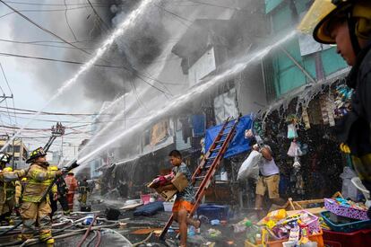 Los bomberos trabajan en la escena de un incendio en un asentamiento informal en Manila.