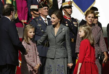 La reina Letizia, vestida de Felipe Varela, junto a la princesa Leonor y la infanta Sofía; y el presidente del Gobierno, Mariano Rajoy, y la ministra de Defensa, María Dolores de Cospedal.