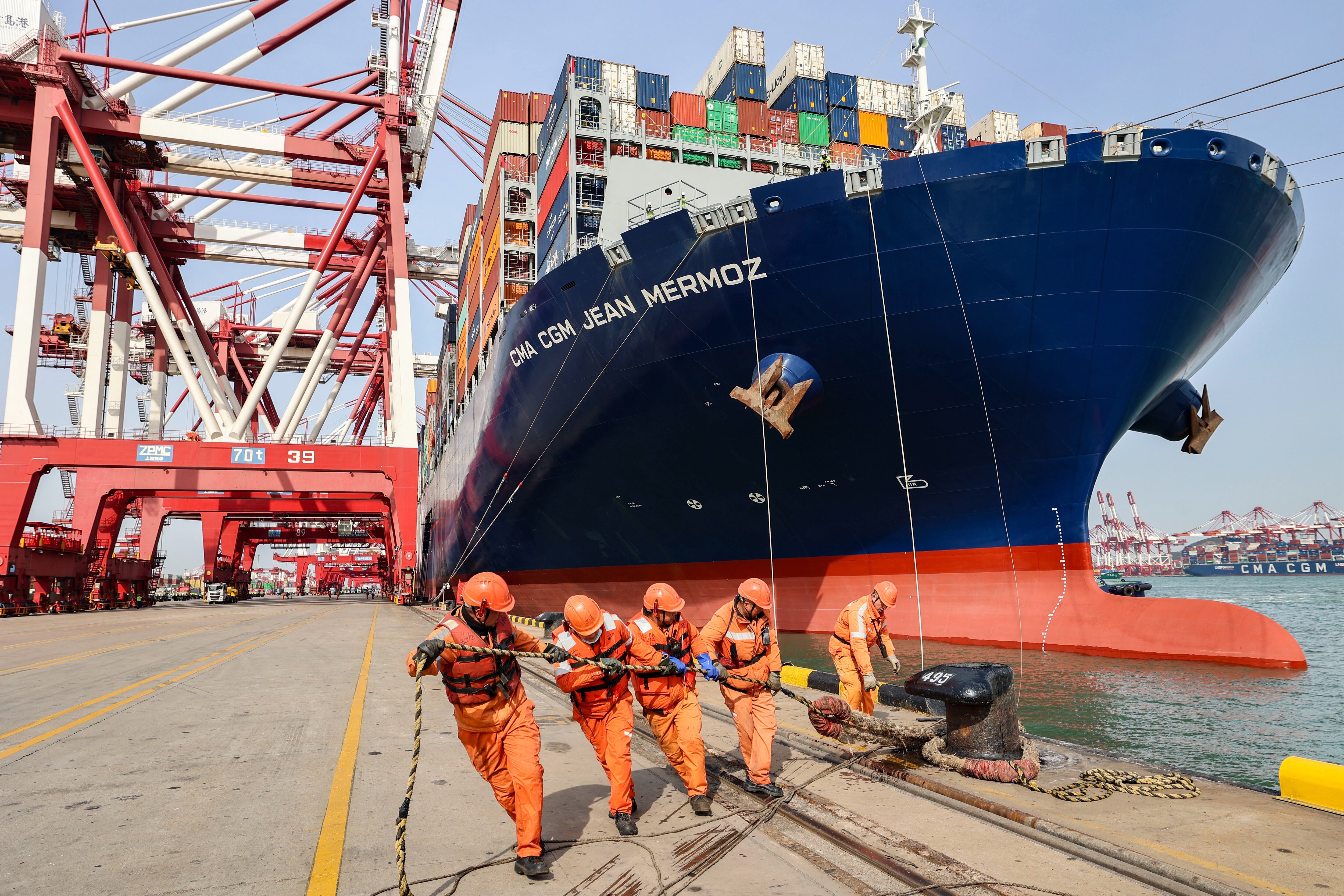 Operadores portuarios ayudan a amarrar un portacontenedores en el puerto de Qingdao (China). 