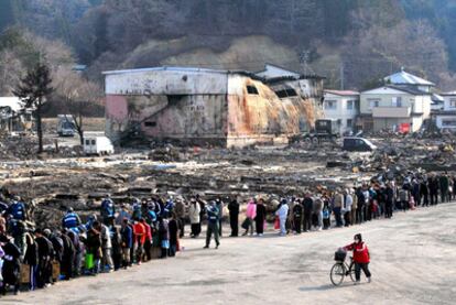 Cientos de damnificados por el tsunami hacen cola para recibir comida y papel higiénico en un reparto organizado por el Ejército en Yamada (prefectura de Iwate).