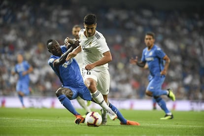 Marco Asensio, del Real Madrid, disputa un balón a Djené del Getafe.