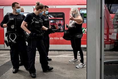 Policías en Colonia (Alemania) reprenden a una mujer por no llevar mascarilla en el transporte público.