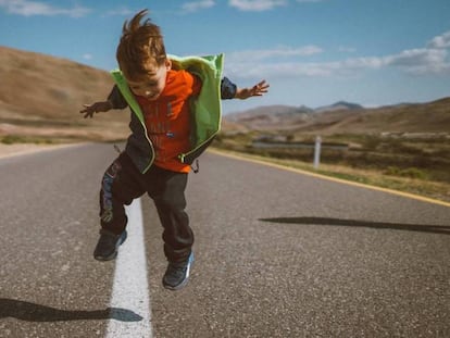 Un niño salta en medio de una carretera vacía. 