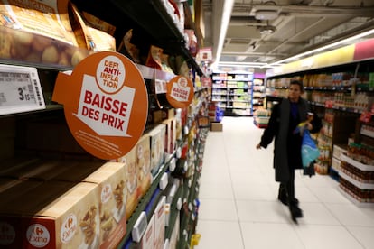 Carteles con el mensaje "Desafío contra la inflación, precios reducidos" en los estantes mientras los clientes hacen sus compras en un hipermercado Carrefour en París, Francia