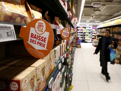 Carteles con el mensaje "Desafío contra la inflación, precios reducidos" en los estantes mientras los clientes hacen sus compras en un hipermercado Carrefour en París, Francia