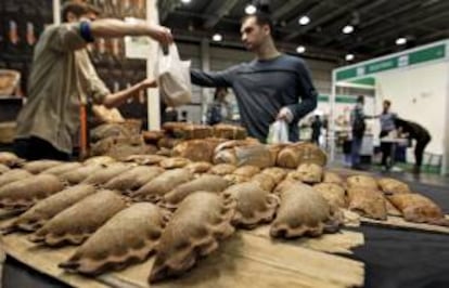 Un visitante de la feria Biocultura, en Valencia, compra pan artesano y ecológico de una de las empresas que participan presentando sus alternativas a la alimentación convencional, contaminada en muchos casos, y muestra las garantías para la salud de este sector.