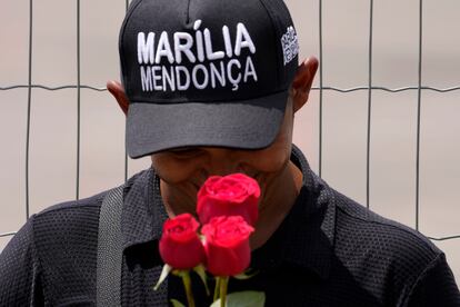 Fã carrega flores na porta do velório da cantora neste sábado.