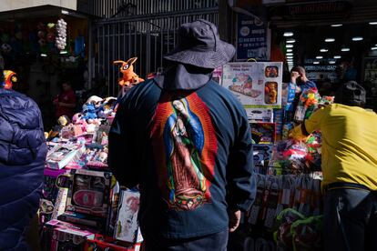 Un comprador que viste una camiseta con la estampa de la virgen María recorre las calles de San Victorino, en Bogotá, el 21 de diciembre de 2022.