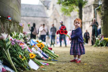 Una niña pone flores en recuerdo a la reina, fuera del palacio de Holyroodhouse en Edimburgo, el lunes.
