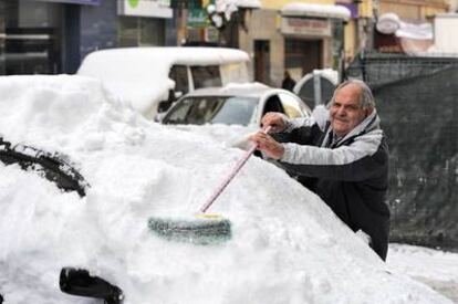 Un hombre trata de limpiar su coche, cubierto de nieve, ayer en Vitoria.