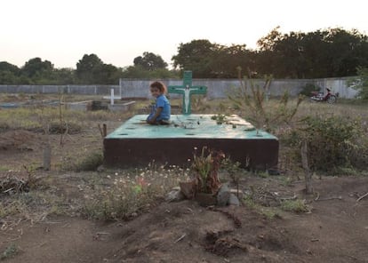 Una ni&ntilde;a sobre una tumba del cementerio de la localidad.