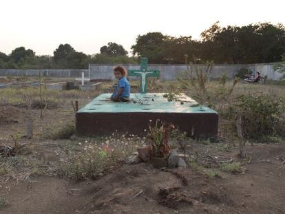 Una ni&ntilde;a sobre una tumba del cementerio de la localidad.