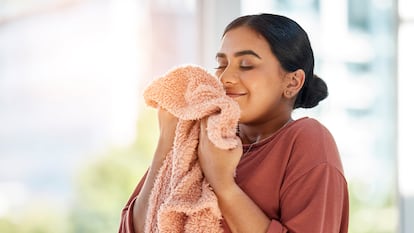 Una chica oliendo la manta en su casa.