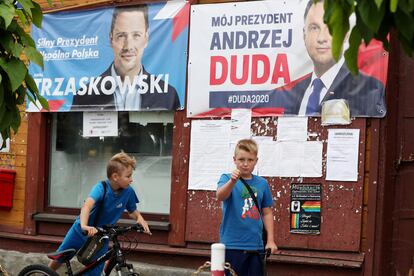 Garotos em frente a cartazes dos candidatos Andrzej Duda e Rafal Trzaskowski, na cidade de Raciaz.