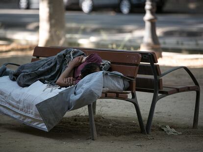 Una persona sin hogar duerme en un banco del paseo de Picasso de Barcelona.