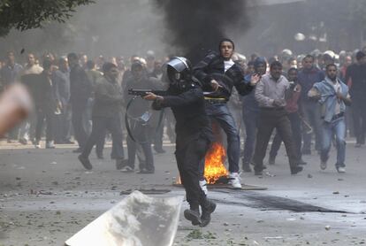 Un policía anti-disturbios apunta con un fusil contra los manifestantes