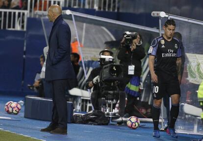 El centrocampista colombiano del Real Madrid, James Rodríguez (d), pasa por detrás del técnico francés del equipo madridista, Zinedine Zidane, tras ser sustituido.