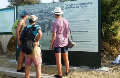 Tres visitantes leen indicaciones de los carteles que llevan a Sant Pere de Rodes.