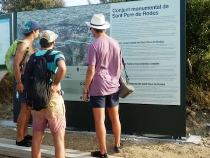 Tres visitantes leen indicaciones de los carteles que llevan a Sant Pere de Rodes.