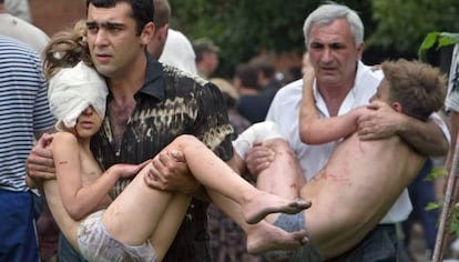 Dois homens carregam crianças resgatadas após a ação das forças russas em Beslan, em 2004 (arquivo).