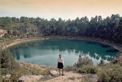 Una excursionista frente a La Gitana, una de las siete lagunas o torcas inundadas de Cañada del Hoyo, en la Serranía Baja de Cuenca.