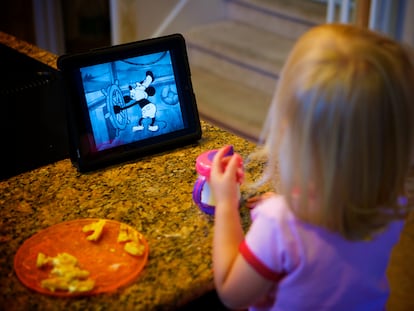 A girl watches a cartoon movie on a tablet.