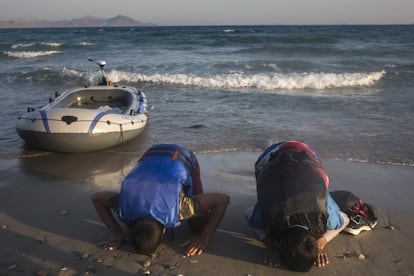 Dos inmigrantes procedentes de Pakistán rezan a su llegada a la costa de la isla griega de Kos.