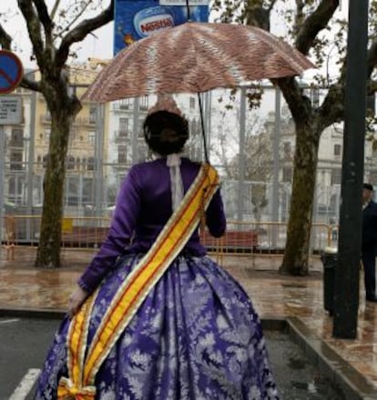 Una fallera con paraguas en la plaza del Ayuntamiento de Valencia.