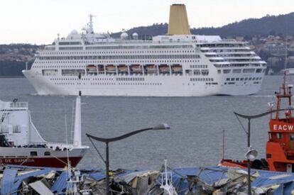 El crucero <i>Oriana </i>abandona el puerto de Vigo. En primer término, los escombros de la nave de cableros.