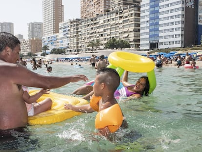 Mario (a la izquierda) juega con Alexander (centro) y Andrea (subida en el flotador), en el agua de la playa de Benidorm.