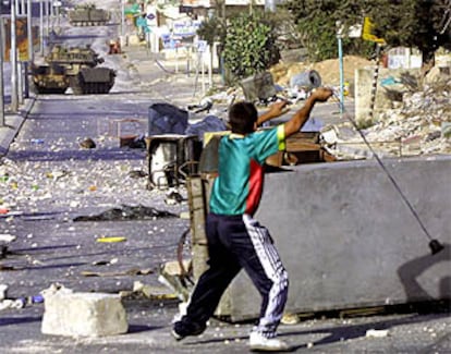 Un adolescente palestino lanza piedras con una honda contra tanques israelíes en Belén, Cisjordania.