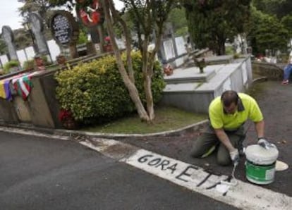 Un operario limpia una pintada a favor de ETA junto a la tumba de Txiki, minutos antes de que empezara el homenaje a éste.