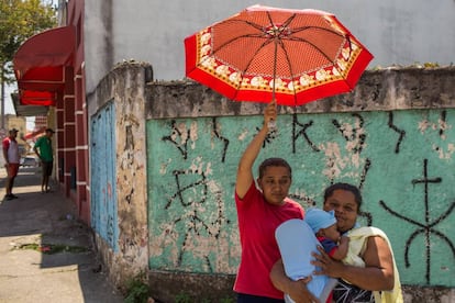 Maria da Dores segura um guarda-chuva ao lado de sua amiga.