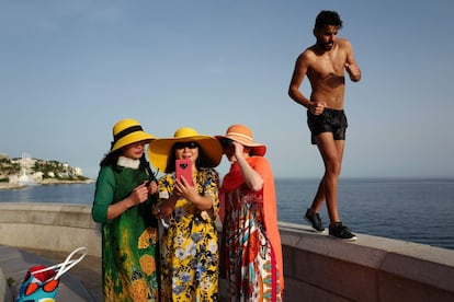 Un hombre camina al lado de tres turistas que se toman un selfie en Niza, Francia, el 24 de junio de 2019.
