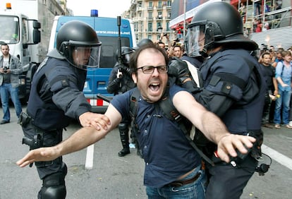 Dos policías intentan sujetar a una de las personas concentradas en la plaza Cataluña de Barcelona.