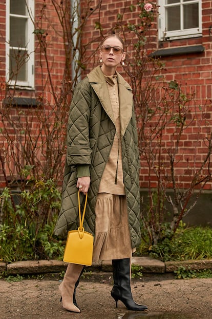 Más allá del abrigo amarillo, que probablemente fue cedido por ambas marcas a las invitadas a sus desfiles, la fiebre por el guateado invadió el street style danés en otro tipo de abrigos, chaquetas y chalecos. Este ejemplo, en verde monte, recuerda a las chaquetas de caza acolchadas que tanto triunfaron en la Inglaterra de los 60 y que se convirtieron en seña estilística de Isabel II. Y también tiene reminiscencias a las batas de estar por casa eternamente asociadas al ouatinée (así se conoce al forro, mientras que el relleno se denomina guata).