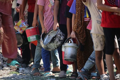 Niños hacen cola con recipientes vacíos en un reparto de comida en el campo de Nuseirat, el viernes 25 de julio.